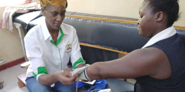 Kenya health promoter Kristine Yakhama (left) checks a patient's blood pressure.