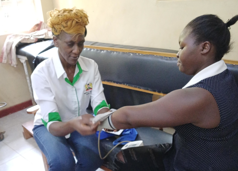 Kenya health promoter Kristine Yakhama (left) at work, warning that the UK aid cuts turn volunteers into "shock absorbers" for shrinking systems.