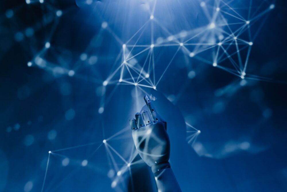 A robotic hand reaching into a digital network on a blue background, symbolising artificial intelligence.