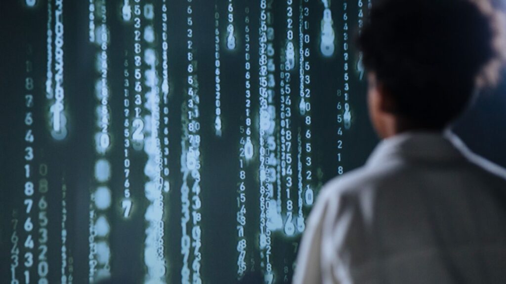 An individual viewing glowing numbers on a screen, symbolising artificial intelligence.